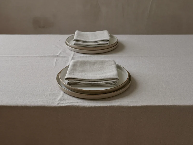 Nappe en lin et serviettes sur une table dressée, vue de dessus.