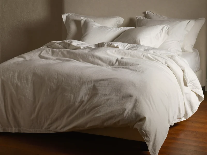 La même chambre sans habillage : matelas nu et draps blancs simples.