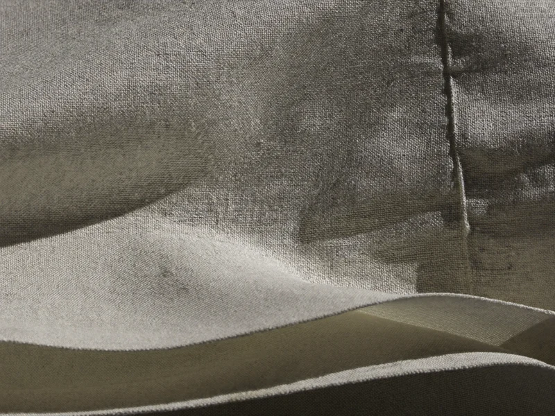 Gros plan sur le tissage du coton et l'ourlet piqué d'un tissu plié.